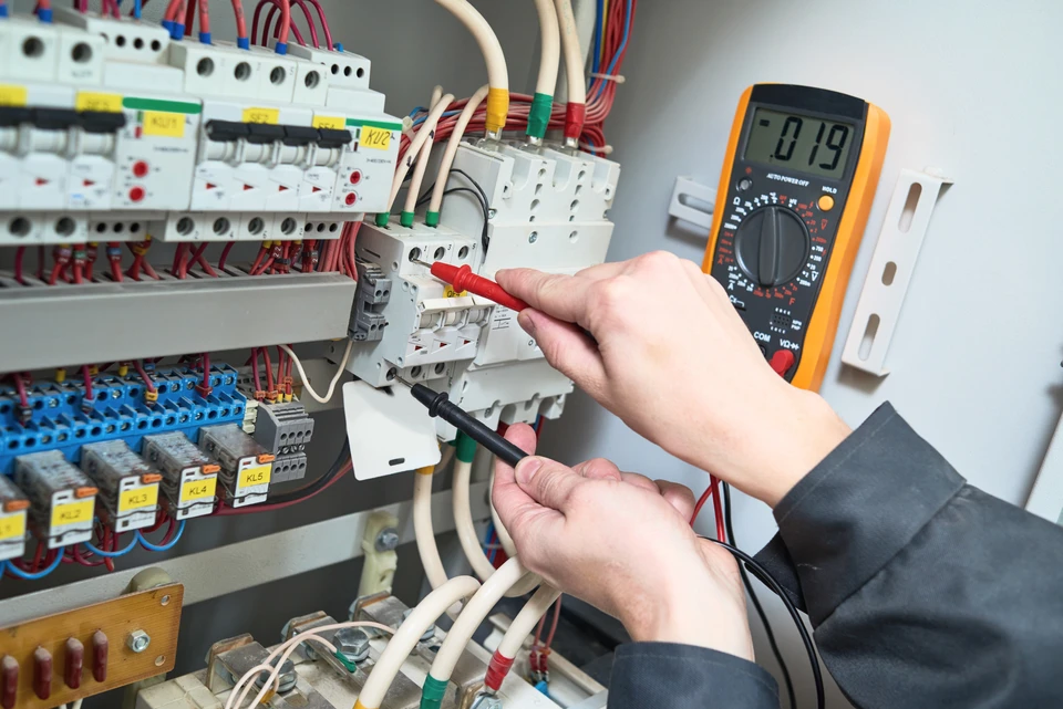 Un &eacute;lectricien effectue des mesures &eacute;lectriques dans un tableau de distribution int&eacute;rieur