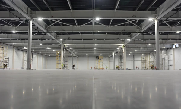 Vaste entrep&ocirc;t industriel en cours d'am&eacute;nagement avec ouvriers &eacute;quip&eacute;s d'&eacute;chafaudages mobiles effectuant des travaux d'installation