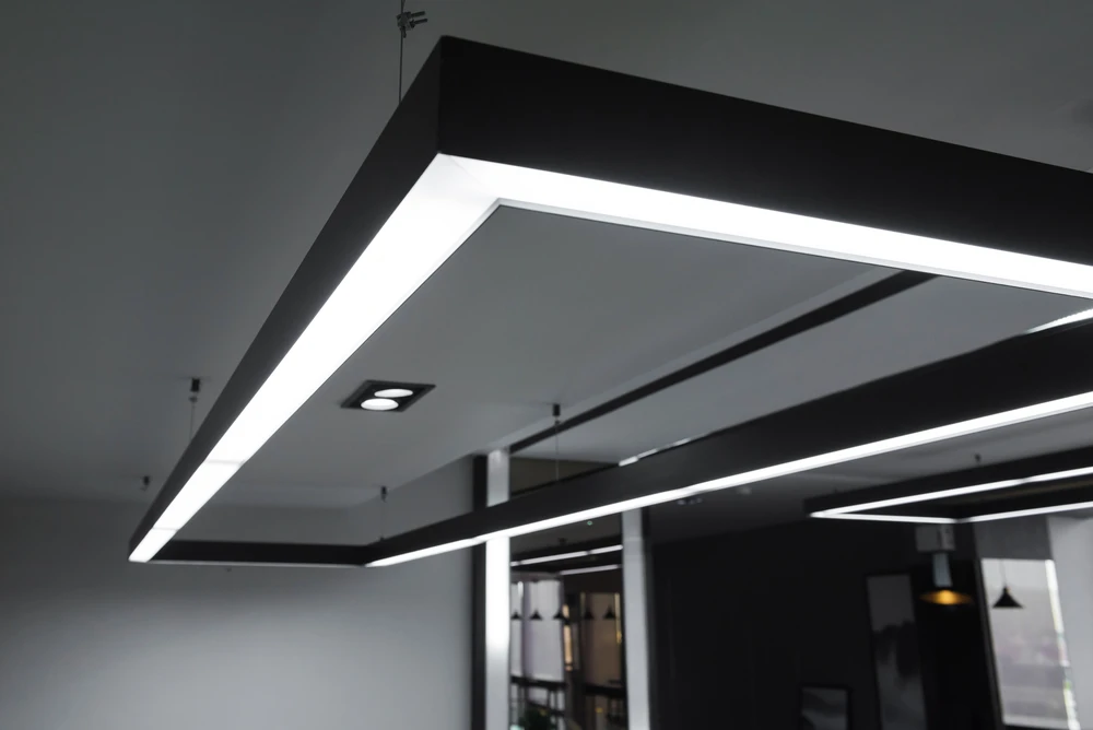 Intérieur de bureau moderne avec plafond suspendu noir intégrant un éclairage LED linéaire blanc continu