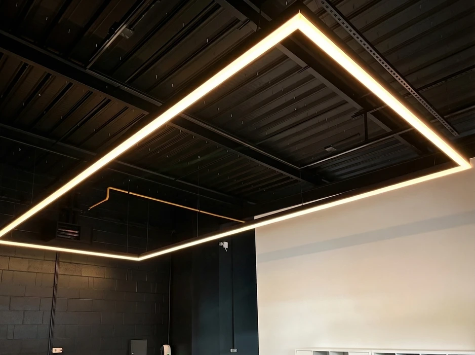 Plafond industriel noir avec un cadre lumineux rectangulaire en LED intégrées, éclairage chaud 3000K