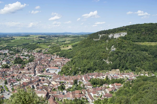 Photographie r&eacute;elle de la ville de Poligny prise en vue panoramique ou a&eacute;rienne, montrant le paysage urbain caract&eacute;ristique de cette commune jurassienne avec ses b&acirc;timents historiques et modernes, ses rues et son environnement, repr&eacute;sentant clairement une zone d'intervention majeure de MGEP. Image en lumi&egrave;re naturelle, professionnelle et clairement identifiable comme Poligny, illustrant l'une des principales villes couvertes par le rayon de 50 km de l'entreprise.