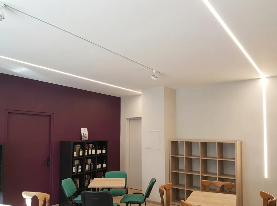 Intérieur de bureau moderne avec plafond suspendu noir intégrant un éclairage LED linéaire blanc continu